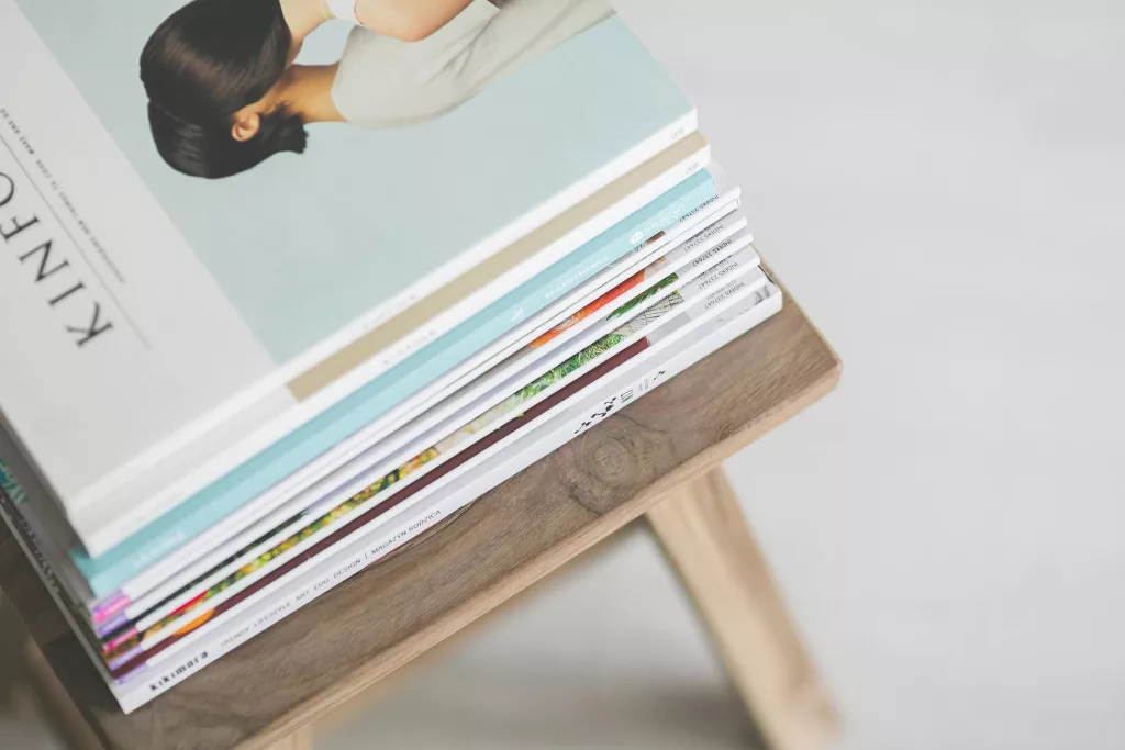 A stack of modern magazines on a wooden stool, perfect for cozy reading.